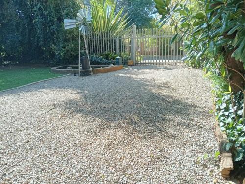 a garden with a fence and a gravel driveway at Be Our Guest Near OR TAMBO International Airport Room 2 in Boksburg