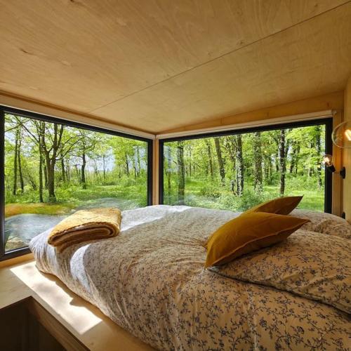 une chambre avec un lit et une grande fenêtre dans l'établissement Tiny House La Clairière au milieu des bois !, à Sonchamp