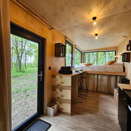 Cette petite maison comprend une cuisine et un lit. dans l'établissement Tiny House La Clairière au milieu des bois !, à Sonchamp