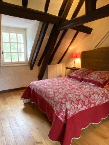 1 dormitorio con 1 cama con colcha roja y ventana en Belle et calme maison de campagne en Artannes-sur-Indre