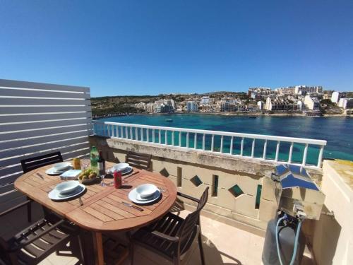 un tavolo su un balcone con vista sull'acqua di Blue Harbour Seafront Penthouse with large terrace with panoramic sea views - by Getawaysmalta a San Pawl il-Baħar