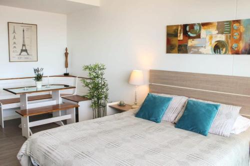a bedroom with a bed with blue pillows and a table at Depto Estudio con Vista al Mar y Estacionamiento Servicio HOM 1016 in Antofagasta