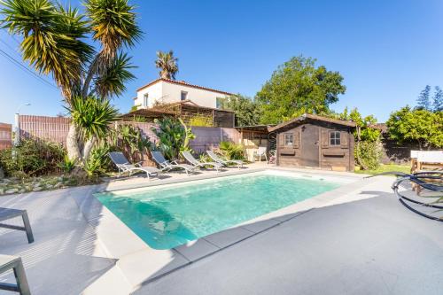 une piscine avec des chaises et une maison dans l'établissement Notre cocon mer et montagne, à Villelongue-de-la-Salanque
