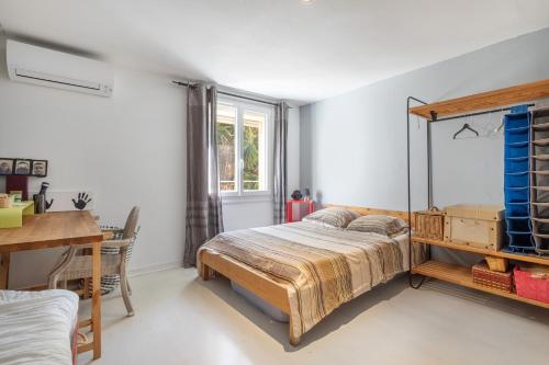 a bedroom with a bed and a desk and a window at Notre cocon mer et montagne in Villelongue-de-la-Salanque