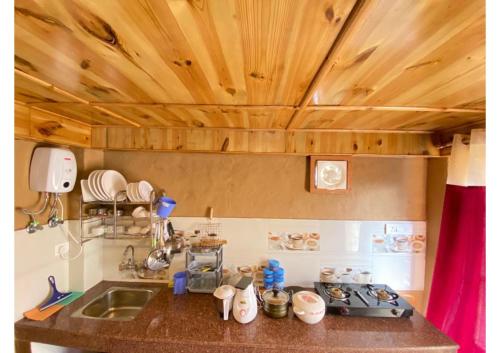 een keuken met houten plafonds en een aanrecht bij Zingo 1BHK Mudhouse in Manāli