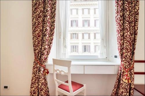 a white chair sitting in front of a window at Fori Imperiali Luxe Mansion in Rome