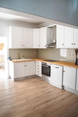 a kitchen with white cabinets and a wooden floor at Casa Azul in Trafaria