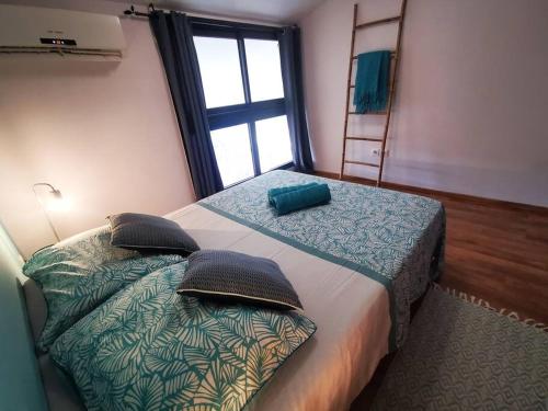 1 dormitorio con cama, escalera y ventana en Appart Hibiscus - piscine - proche du lagon en Saint-Paul