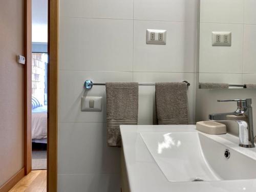 een witte badkamer met een wastafel en een spiegel bij Comodo Depto, en Puerto Varas Gran Terraza y Parking Servicio HOM in Puerto Varas
