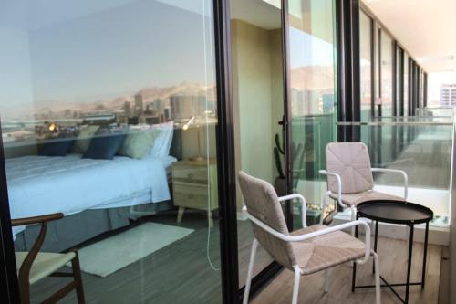 - une chambre avec un lit, deux chaises et une table dans l'établissement Departamento 1D1B con Terraza vista al Mar Servicio HOM 0810, à Antofagasta