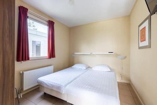 een slaapkamer met een wit bed en een raam bij Vakantiechalet de Wilgenroos 142 in Wervershoof