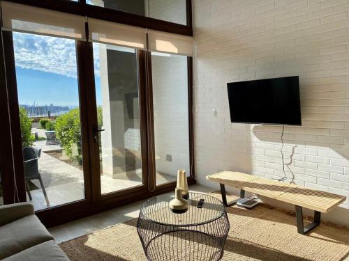 Una sala de estar con un televisor, un sofá y una mesa. en HOM I Amplio Loft con Jardín en MejorLugar de Valparaíso 1109, en Valparaíso