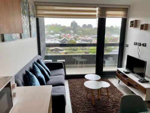 a living room with a couch and a large window at HOM I Con parking incluido Depto 1D1B in Puerto Varas