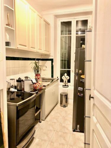une cuisine avec des armoires blanches et un réfrigérateur noir dans l'établissement APPARTEMENT NICE le PORT, à Nice