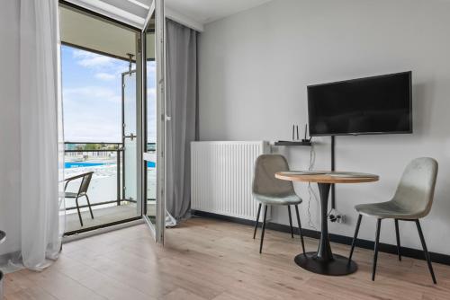 a living room with a table and chairs and a tv at RentPlanet - Apartamenty Wiktoryn in Warsaw