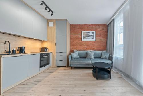 a kitchen and a living room with a couch at RentPlanet - Apartamenty Wiktoryn in Warsaw