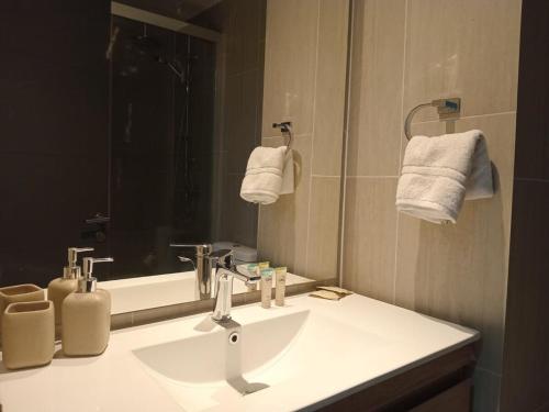 een badkamer met een wastafel, een spiegel en handdoeken bij Familiar Depto cercano al Centro y a la Costaner Servicio HOM in Puerto Varas