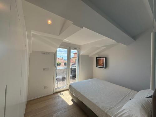 a white bedroom with a bed and a large window at Doria House in Imperia