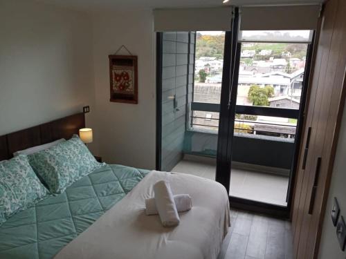 1 dormitorio con 1 cama y vistas a un balcón en Cómodo Depto Nuevo en la Mejor Zona de Pto Varas Servicio HOM, en Puerto Varas