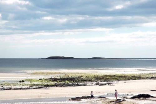 two people standing on a beach with a surfboard at Islands View in Wexford