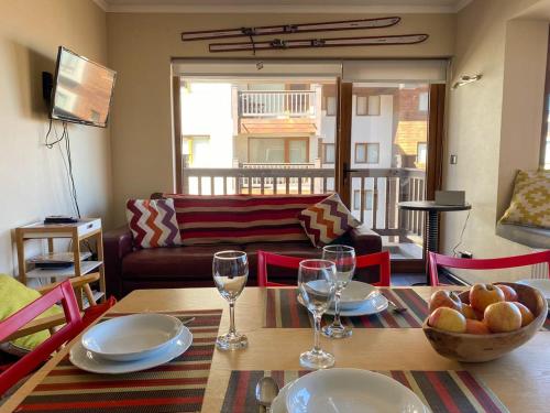 ein Wohnzimmer mit einem Tisch mit Tellern und Weingläsern in der Unterkunft Edif El Plomo Acogedor Depto en Valle Nevado 6PAX Servicio HOM in Farellones