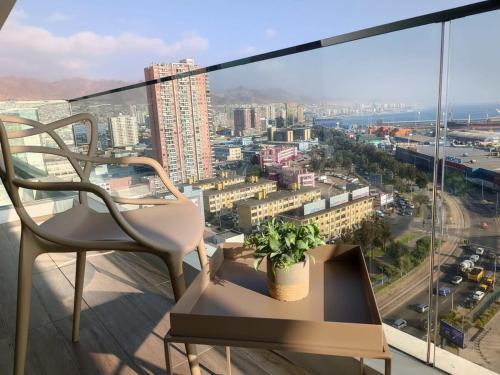 a chair and a plant on a balcony with a view at HOM I Dúplex con Terraza y Parking con vista al Mar 1118 in Antofagasta