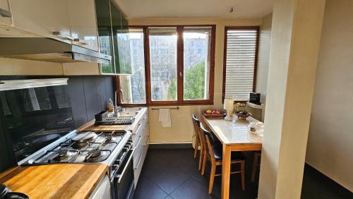 une cuisine avec une cuisinière et une table à l'intérieur dans l'établissement Big & calm familial apartment with balcony, car parking and free wifi, à Villejuif
