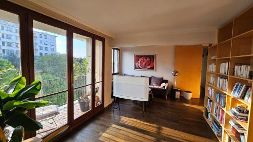 ein Wohnzimmer mit einem Schreibtisch und einem großen Fenster in der Unterkunft Big & calm familial apartment with balcony, car parking and free wifi in Villejuif