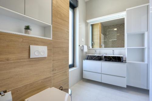 a bathroom with a sink and a toilet and a mirror at Villa Didov San Family Residence with Pool in Zaton