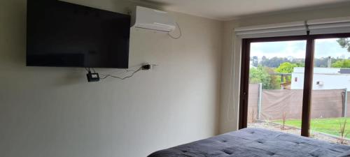 a bedroom with a flat screen tv on the wall at HOM I Casa en Condominio Alto Lomas a 3min de Marbella con Piscina y Jacuzzi in Maitencillo