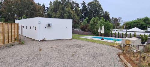 a large white garage next to a swimming pool at HOM I Casa en Condominio Alto Lomas a 3min de Marbella con Piscina y Jacuzzi in Maitencillo