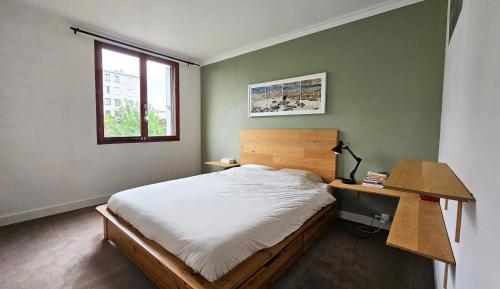 une chambre avec un lit, un bureau et une fenêtre dans l'établissement Big & calm familial apartment with balcony, car parking and free wifi, à Villejuif