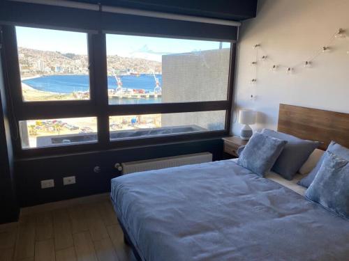 - une chambre avec un grand lit et une grande fenêtre dans l'établissement Acogedor 2D2B, En Cerro Barón con estacionamiento Servicio HOM, à Valparaíso