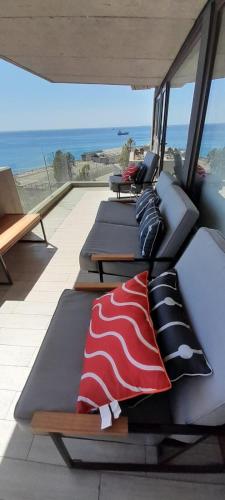 a row of chaise lounges on a balcony with the ocean at HOM I AMPLIO 4D3B Mejor ubicación Valparaíso Parking 6PAX in Valparaíso