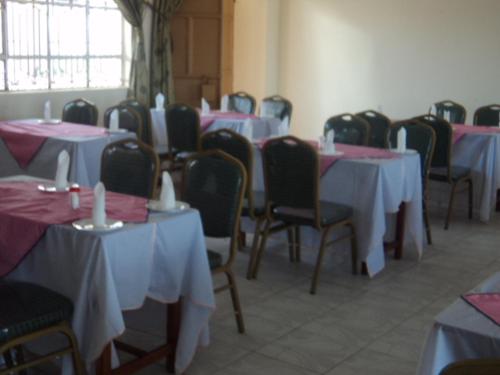 een kamer gevuld met tafels en stoelen met roze en witte tafels bij NEDLAND INN in Konza