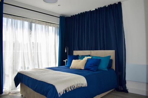 a blue bedroom with a bed with blue curtains at Hemel Apartments- Riverside Retreat in Hemel Hempstead
