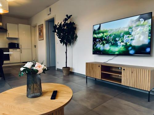 a living room with a tv and a vase of flowers on a table at FeWo Am Povelturm Aufzug & Loggia in Nordhorn