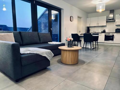ein Wohnzimmer mit einem Sofa und einem Tisch in der Unterkunft FeWo Am Povelturm - mit Aufzug und großer Loggia in Nordhorn