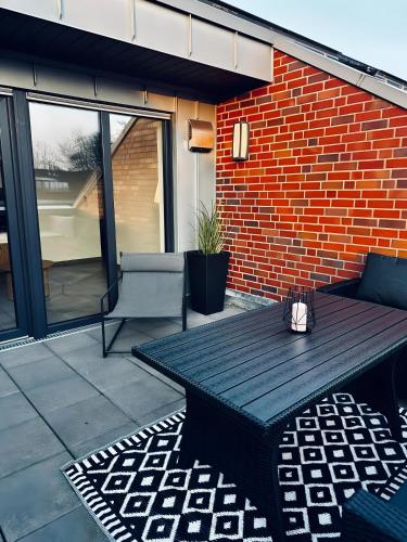 a patio with a table and a brick wall at FeWo Am Povelturm Aufzug & Loggia in Nordhorn