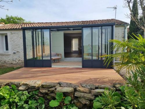 a house with glass doors and a stone wall at O Pressoir in Le Pellerin