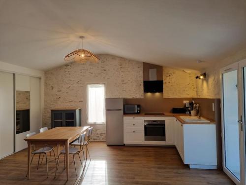 een keuken met een houten tafel en witte apparaten bij O Pressoir in Le Pellerin