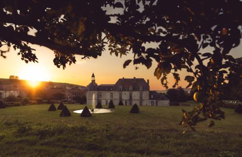 an old building in a field with the sunset in the background at Le Château d'Etoges - Champagne in Étoges