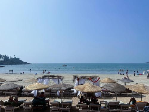 un grupo de personas sentadas en una playa con sombrillas en Art Resort Goa, en Palolem