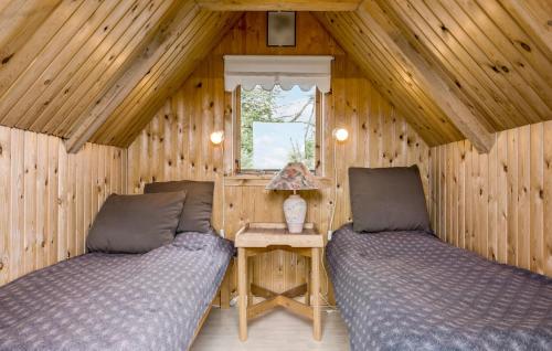 3 Bedroom Lovely Home In rsted في Ørsted: غرفة نوم بسريرين في كابينة خشبية