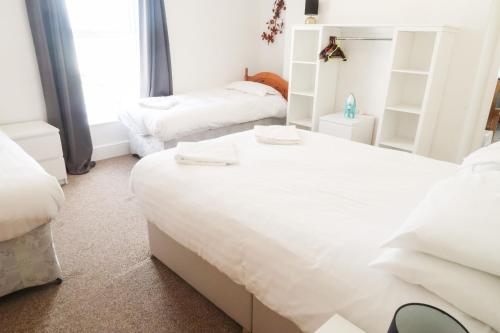 a white bedroom with two beds and a window at Farina No8, 3 bedroom Sea view apartment sleeping 7 guests in Bridlington