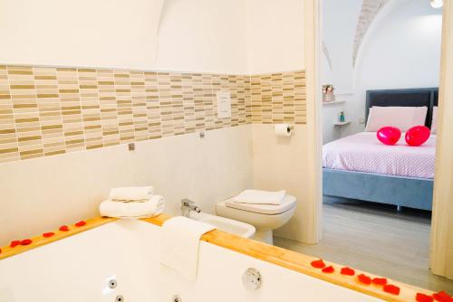 La salle de bains est pourvue d'une baignoire, de toilettes et d'un lit. dans l'établissement Suite Votano 24 - RELAX nel CUORE ANTICO di CEGLIE, à Ceglie Messapica