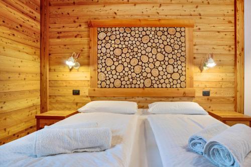 two beds in a wooden room with a window at Chalet Camping Faè 8 - Trilocale in Madonna di Campiglio