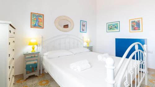 a white bedroom with a white bed and a dresser at Panorama Blu in S'archittu Cuglieri