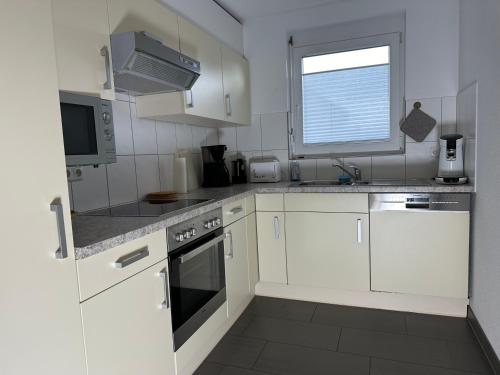 a white kitchen with white cabinets and a window at Ferienwohnung Bodenseeblick in Hagnau