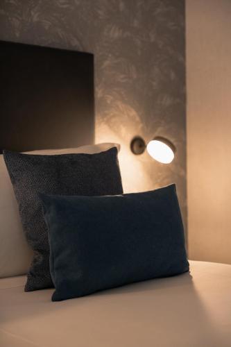 a black pillow sitting on a bed with a lamp at H2C Hotel Milanofiori in Assago
